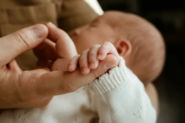 Main d'un parent tenant délicatement la petite main d'un nouveau-né
