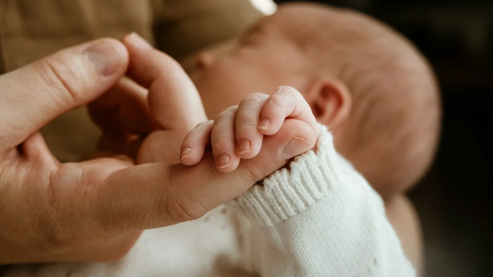 Main d'un parent tenant délicatement la petite main d'un nouveau-né