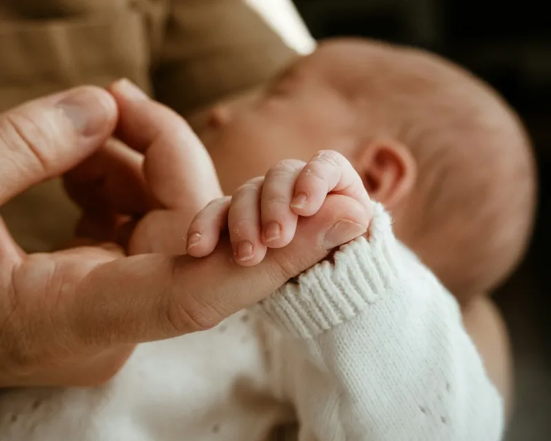 Main d'un parent tenant délicatement la petite main d'un nouveau-né
