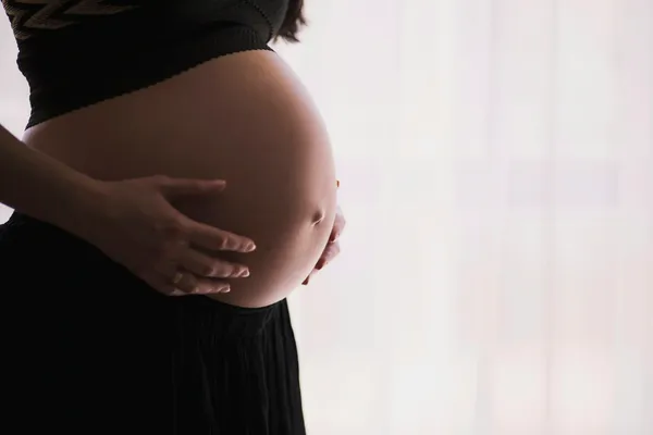 Femme enceinte berçant son ventre dans une lumière douce
