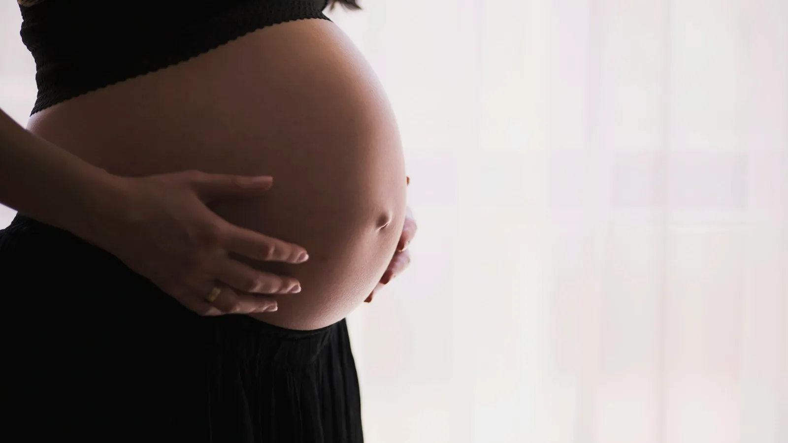 Femme enceinte berçant son ventre dans une lumière douce