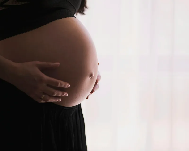 Femme enceinte berçant son ventre dans une lumière douce